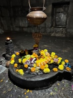 Shiva lingam adorned with flowers and a snake statue.