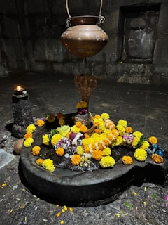 Shiva lingam adorned with flowers and a snake statue.