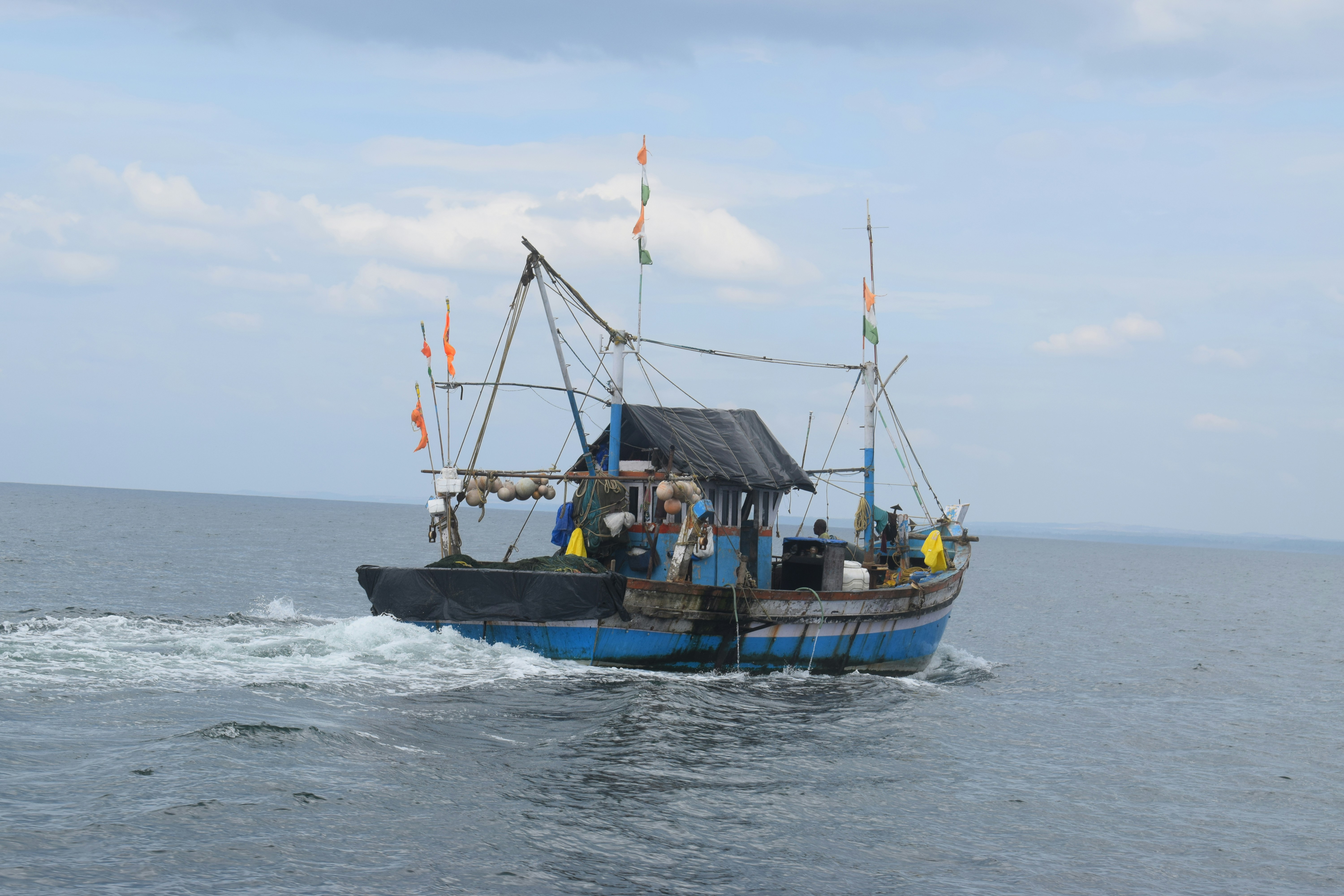 A blue fishing boat sails on the ocean