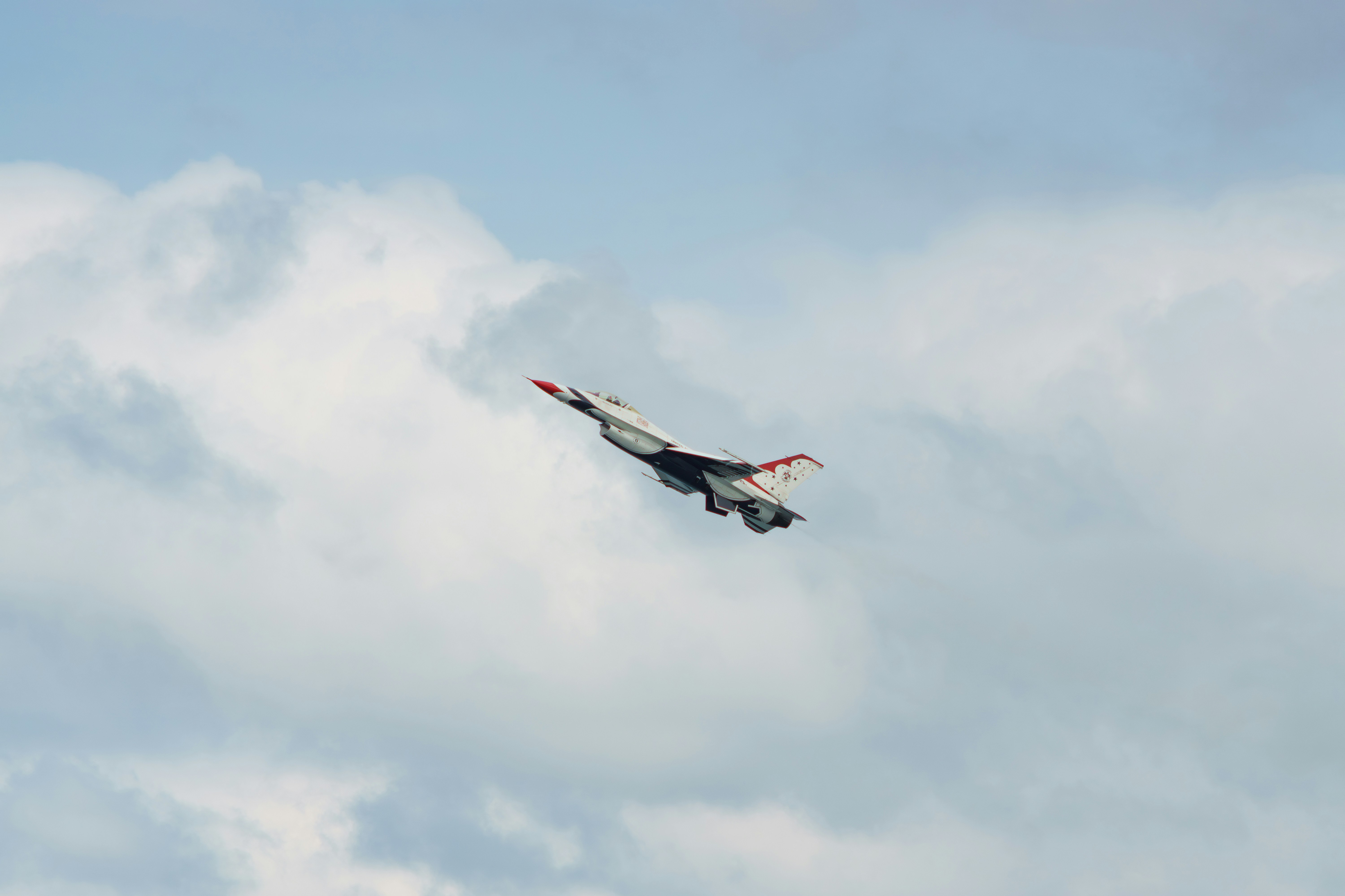 A fighter jet performs a maneuver against a cloudy sky.