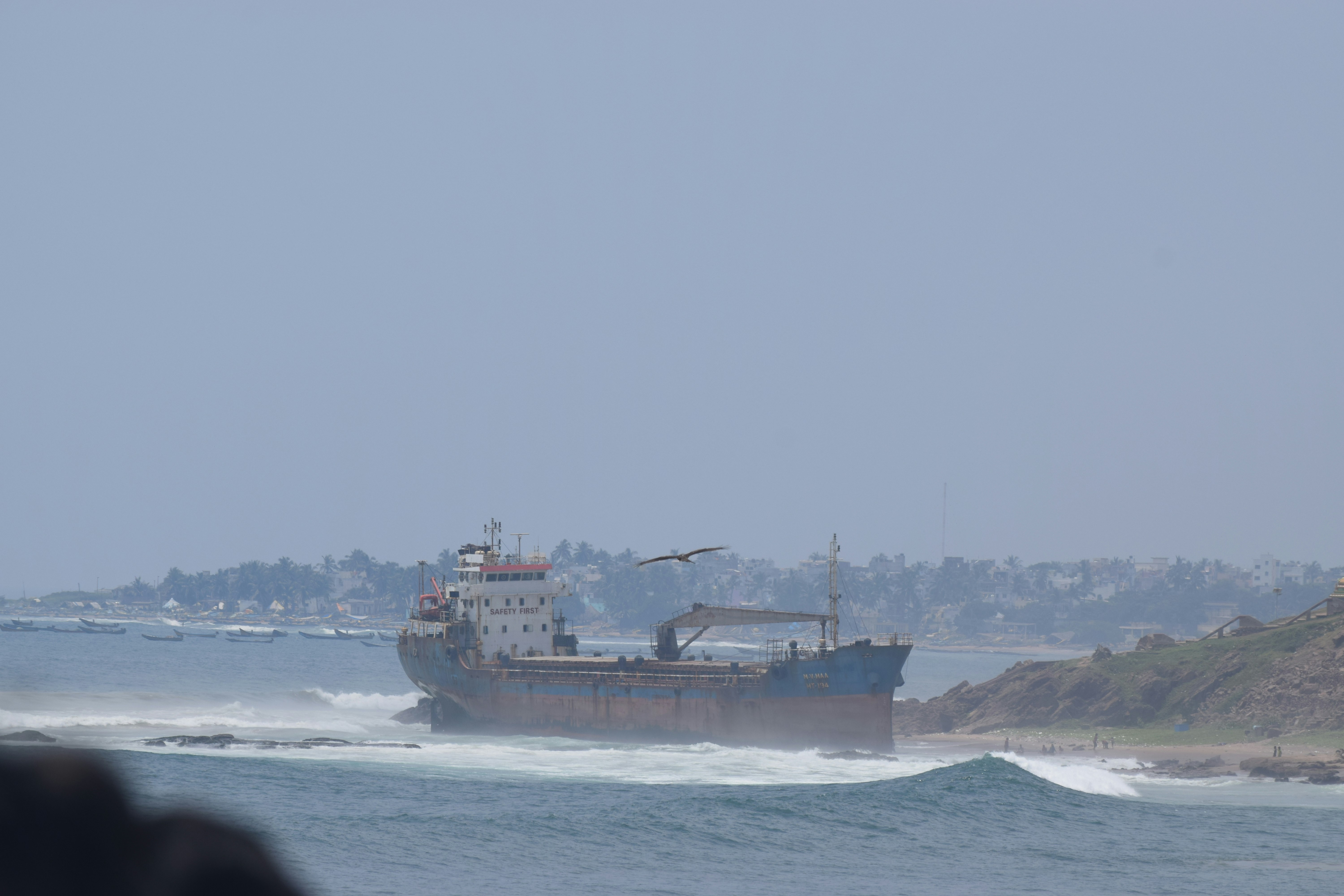 Ship grounded on a rocky shore with waves crashing.