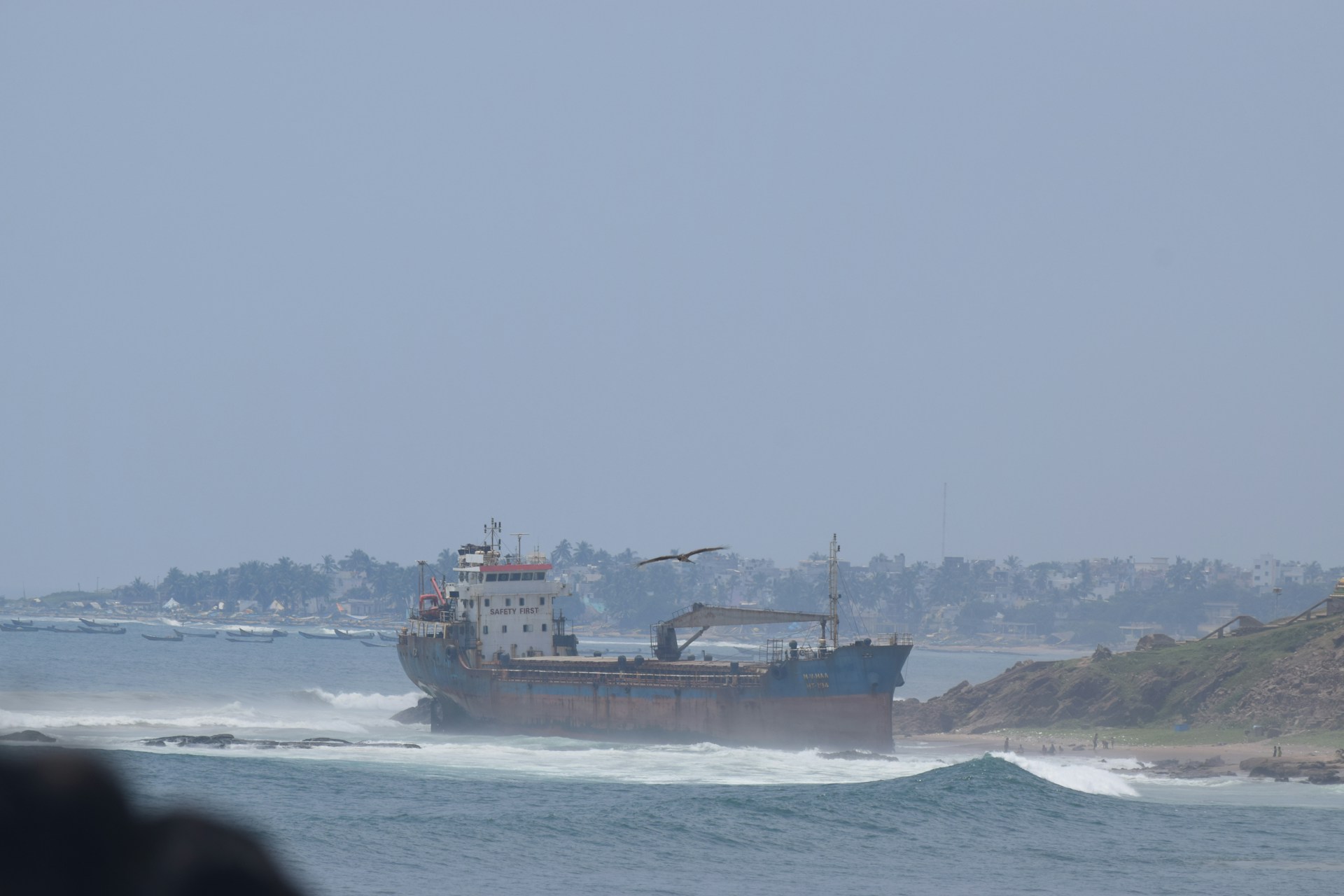 Ship grounded on a rocky shore with waves crashing.