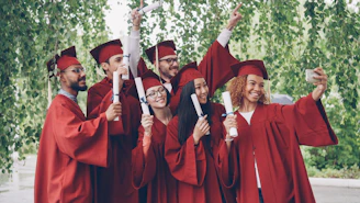 Graduates in red robes taking a selfie with diplomas