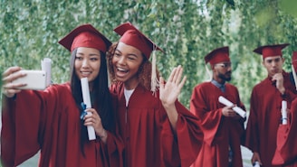 Graduates in caps and gowns taking a selfie outdoors.