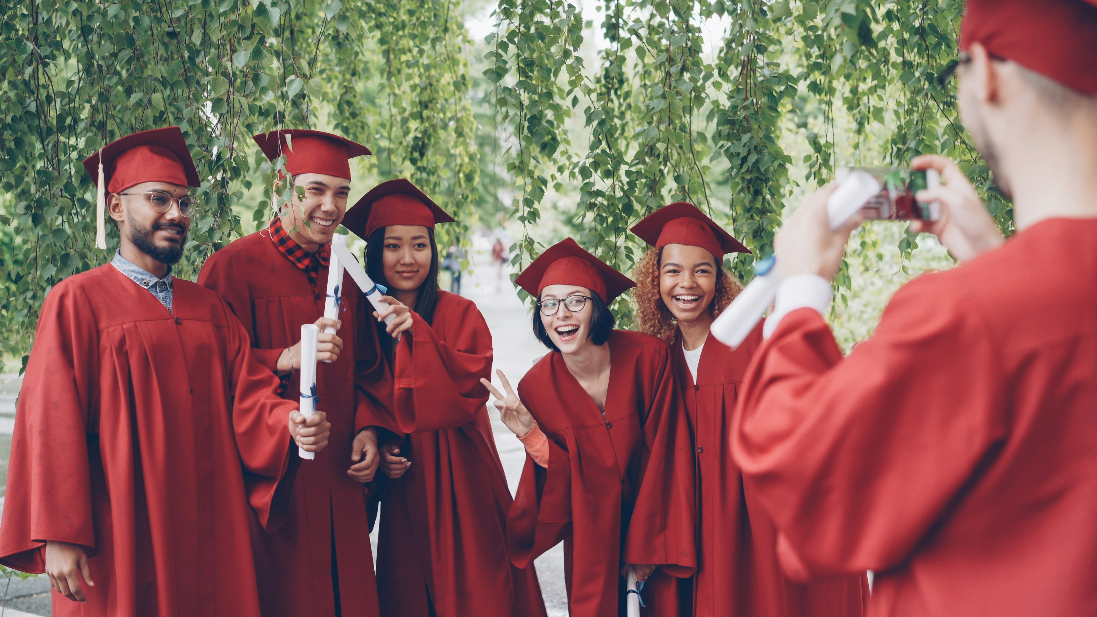 Graduates in red robes pose for a group photograph.