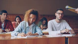 Students attentively taking notes in a lecture hall.