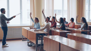Teacher pointing at students with raised hands