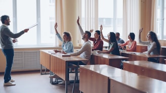 Teacher pointing at students with raised hands