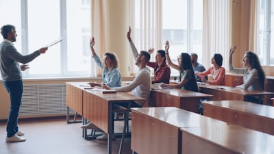 Teacher pointing at students with raised hands