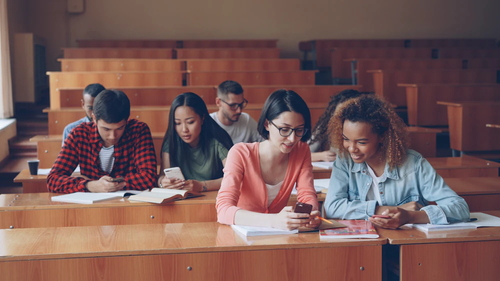 College students using their phones during a break in a lecture hall