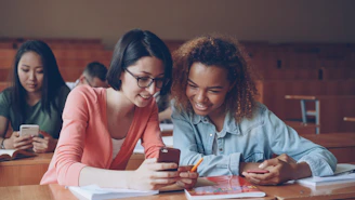Two students looking at a smartphone in class.