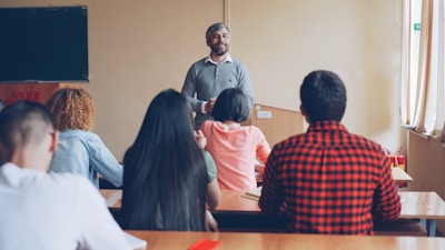 Teacher lecturing students in a classroom setting.