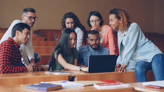 Diverse group of students gathered around a laptop.