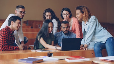 Diverse group of students gathered around a laptop.