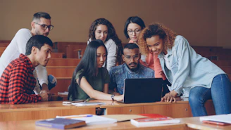 Diverse group of students gathered around laptop