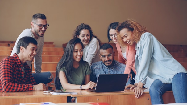Diverse group of students gathered around a laptop.