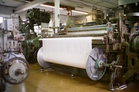 Industrial looms with large spool of white thread