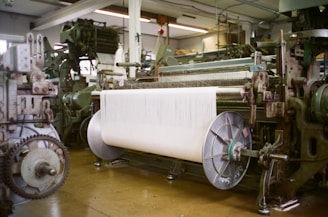 Industrial looms with large spool of white thread