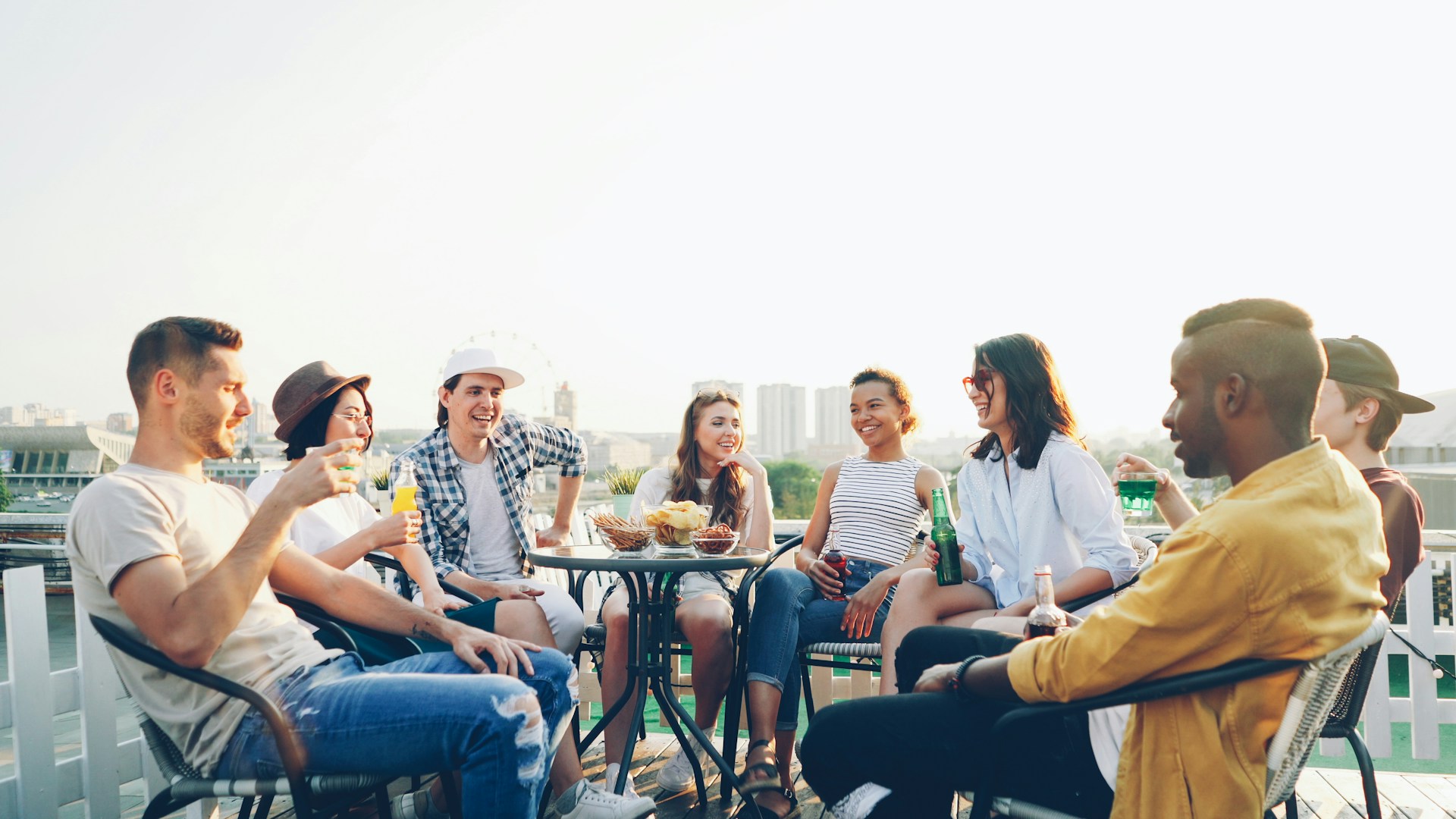 Friends enjoying drinks and snacks on a rooftop.