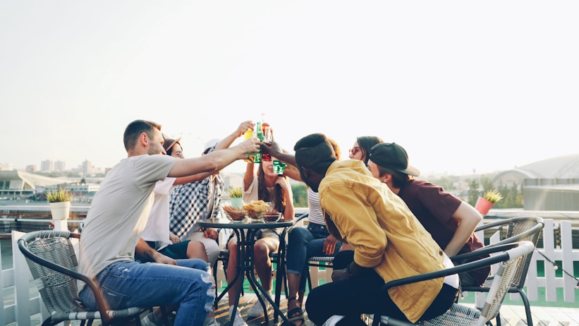Friends toasting drinks on a sunny rooftop patio.