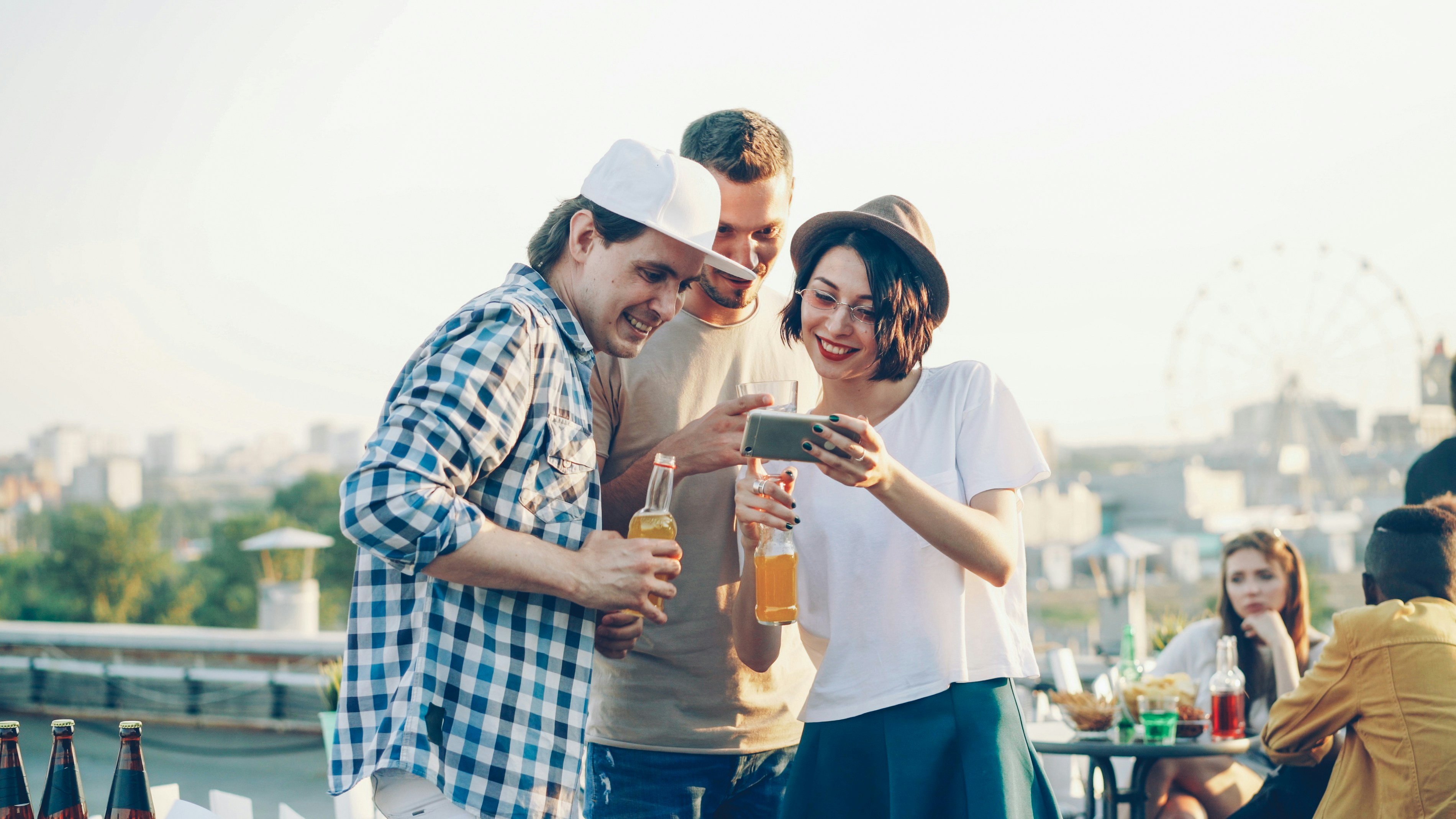 Three friends crowded around a phone, laughing, possibly listing to a spiralling AI chatbot conversation 