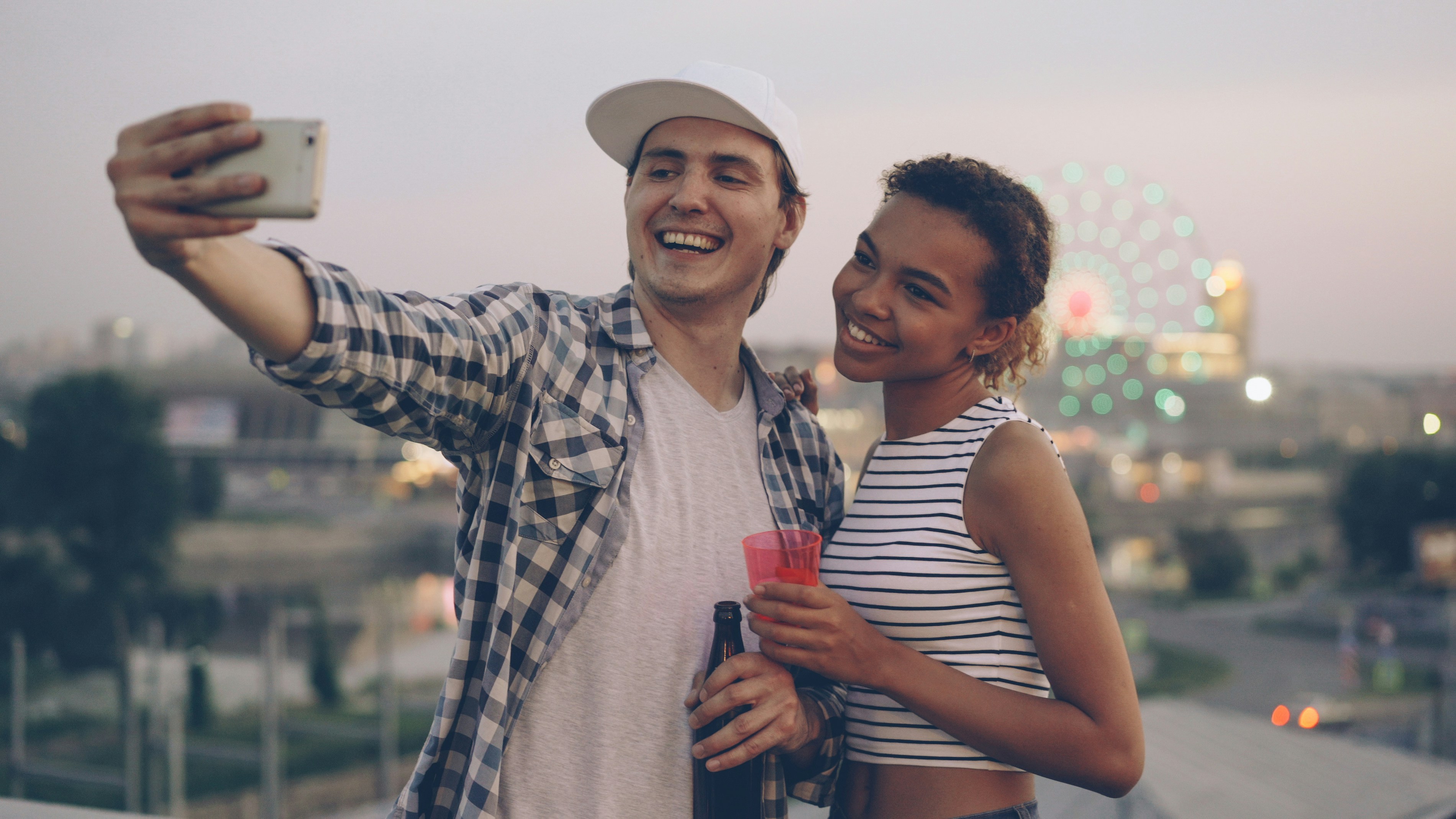 Couple taking a selfie with city lights in background