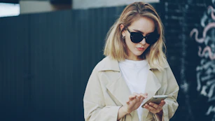 Woman in sunglasses using a smartphone outdoors