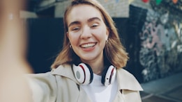 Young woman smiling while taking a selfie outdoors.