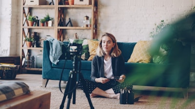Woman filming herself with a camera in a living room.