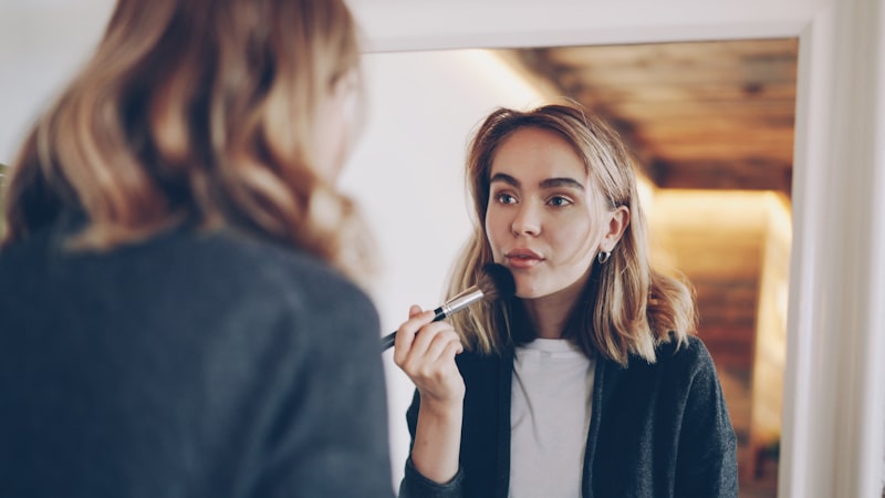 Persona che si prepara davanti allo specchio con prodotti cosmetici