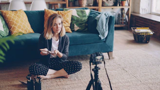 Woman filming herself with a camera in a living room