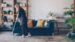 Woman cleaning the floor in a modern living room.