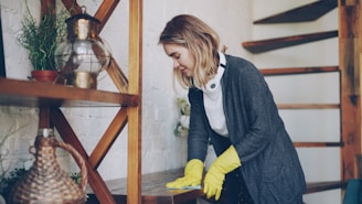 Woman wearing yellow gloves cleaning wooden surface