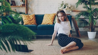 Young woman sitting on floor with laptop in living room.