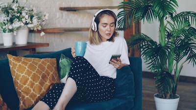 Woman listening to music on phone while holding mug.