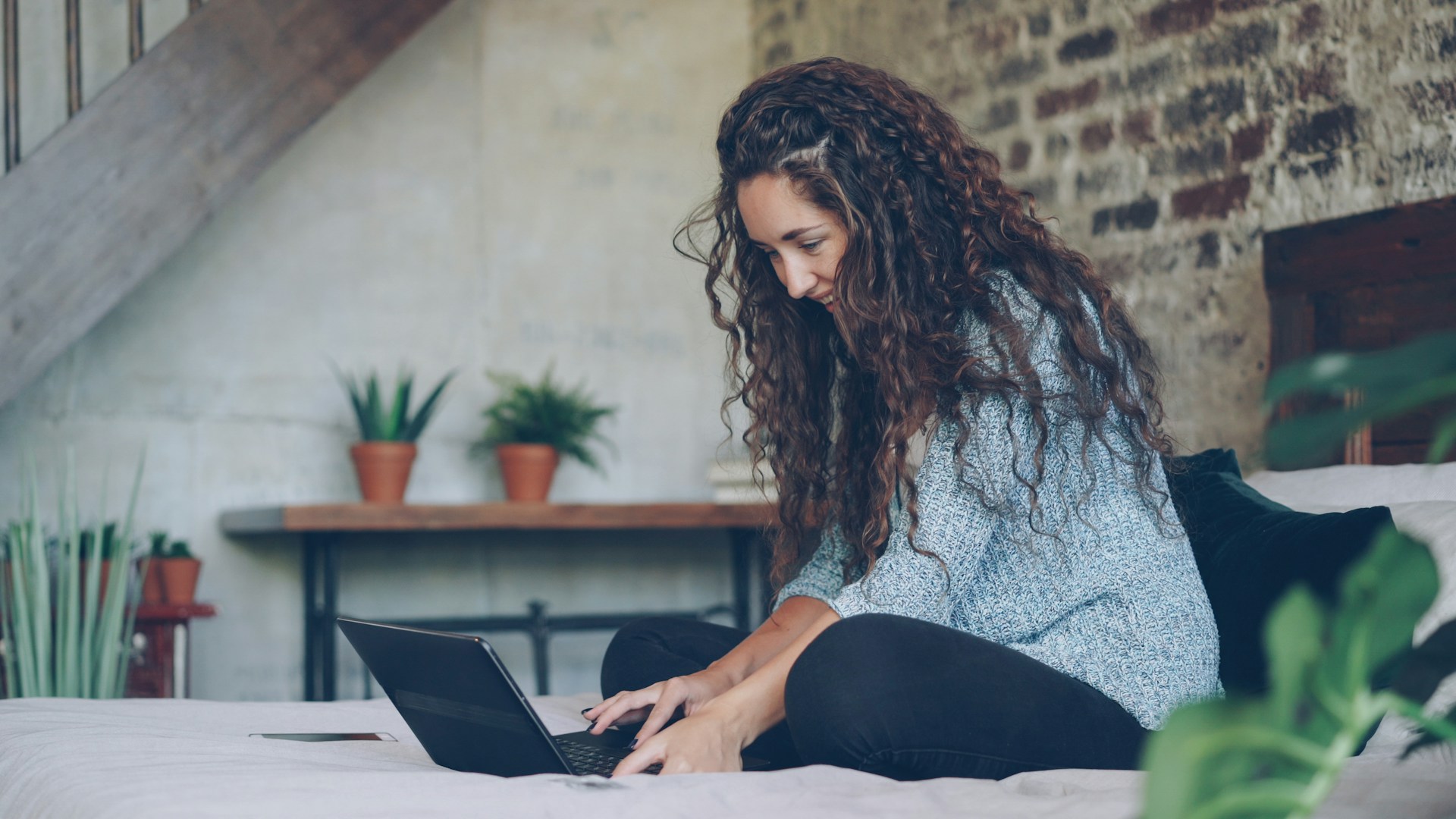 Woman with curly hair typing on a laptop