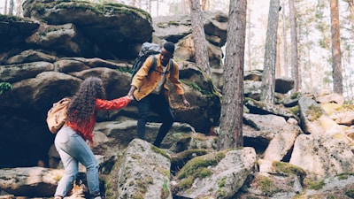 Two hikers helping each other climb rocky terrain
