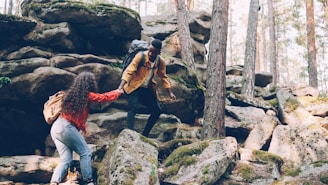 Two hikers helping each other climb rocky terrain