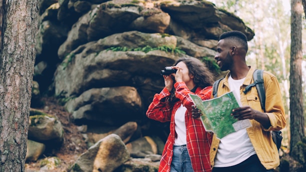 Couple hiking with binoculars and map in forest