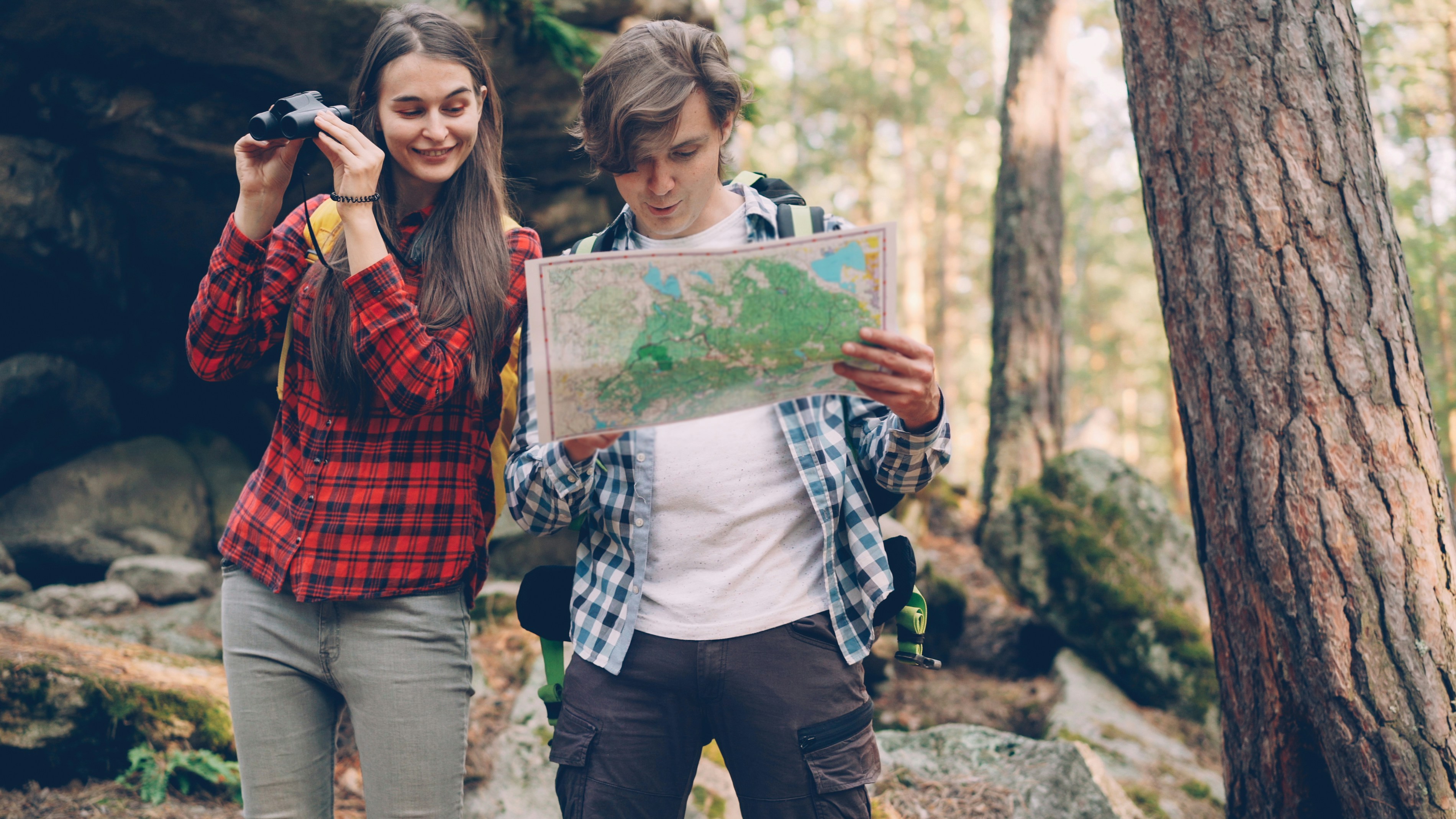 Couple planning mountain trip with map and binoculars