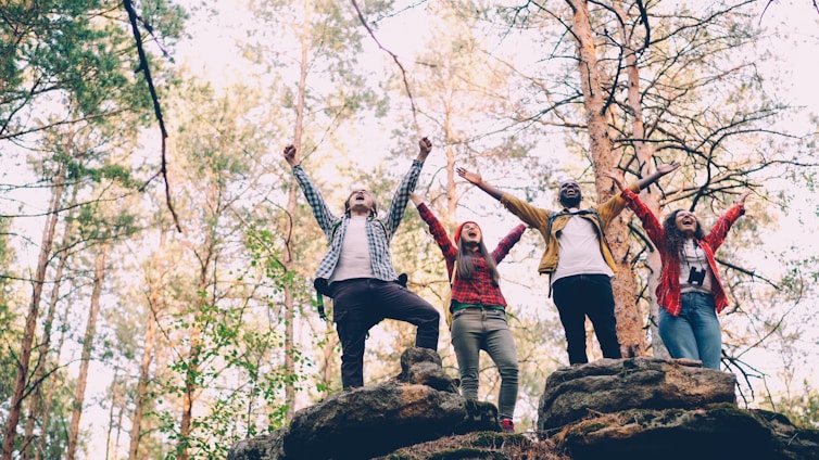 Four friends celebrating on rocky terrain outdoors