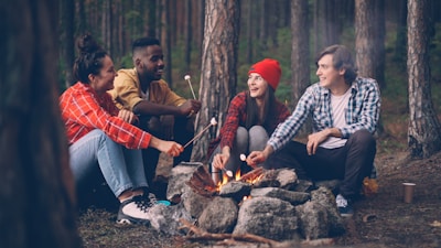 Friends roasting marshmallows around a campfire in the woods.