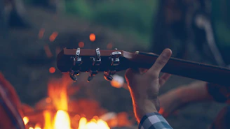 Playing guitar by a campfire at night.