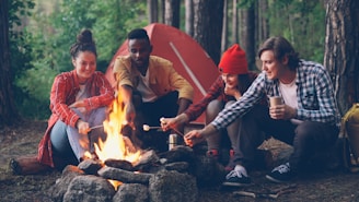 Friends roasting marshmallows around a campfire at campsite.