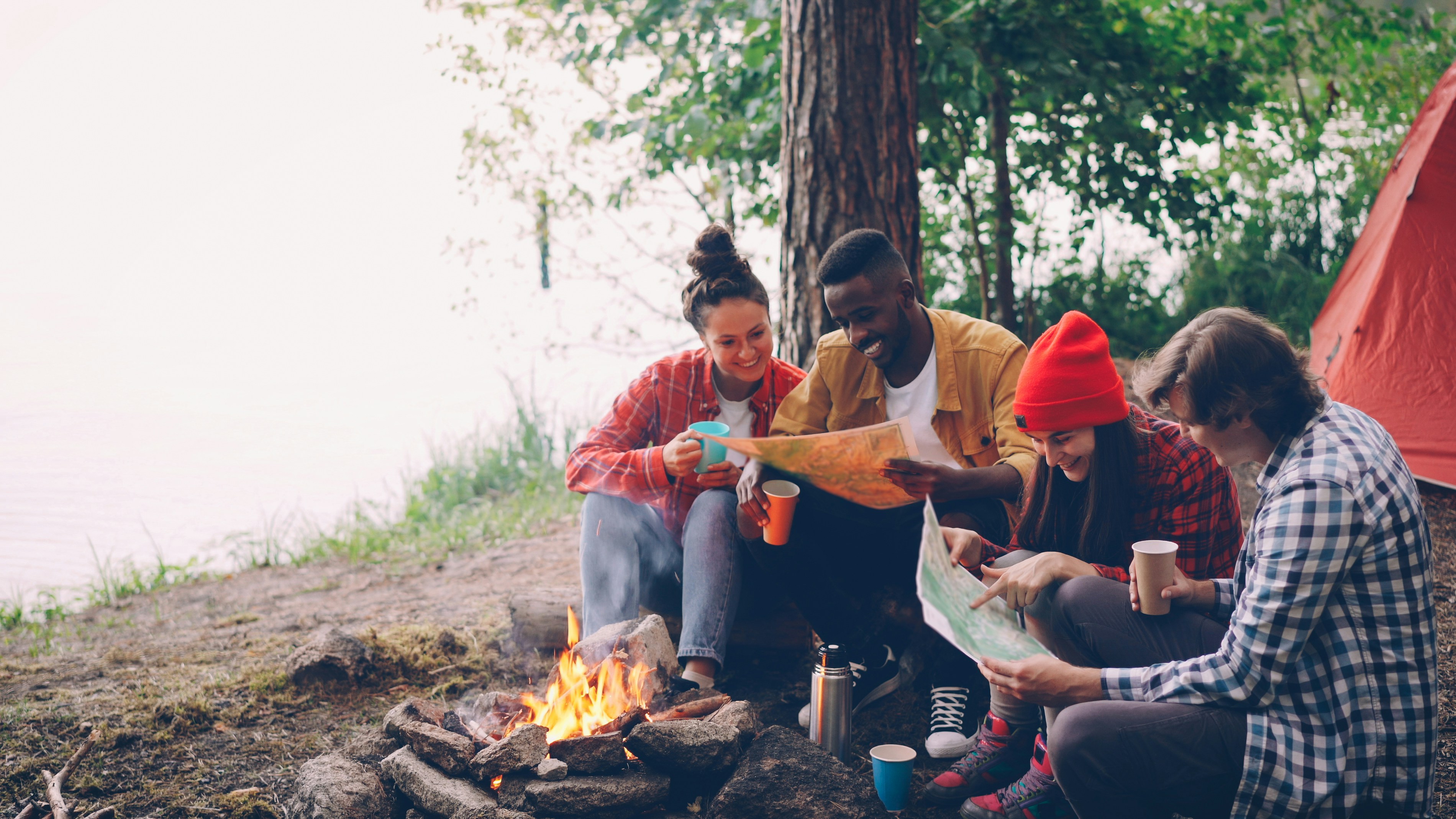 Friends planning adventure around campfire