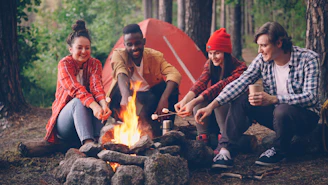 Friends roasting marshmallows around a campfire at night
