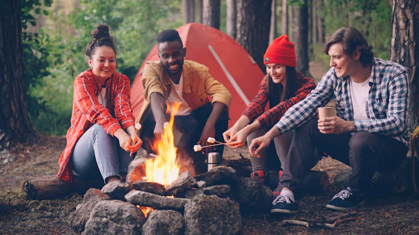Friends roasting marshmallows around a campfire at night