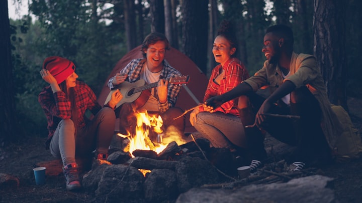 Friends laughing together around a campfire in the woods