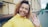 Young woman in yellow jacket waves hello outdoors