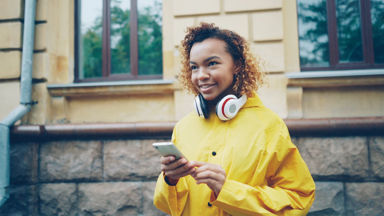 Mulher sorrindo ao olhar o celular, recebendo o dinheiro na conta